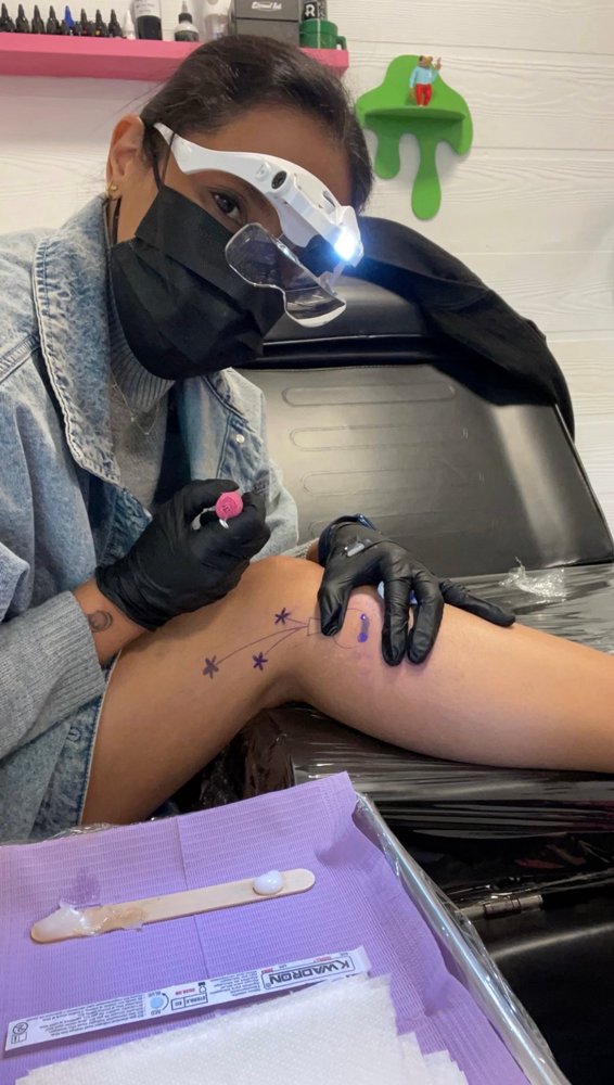 Sheila working on a hand poke tattoo with a magnifier